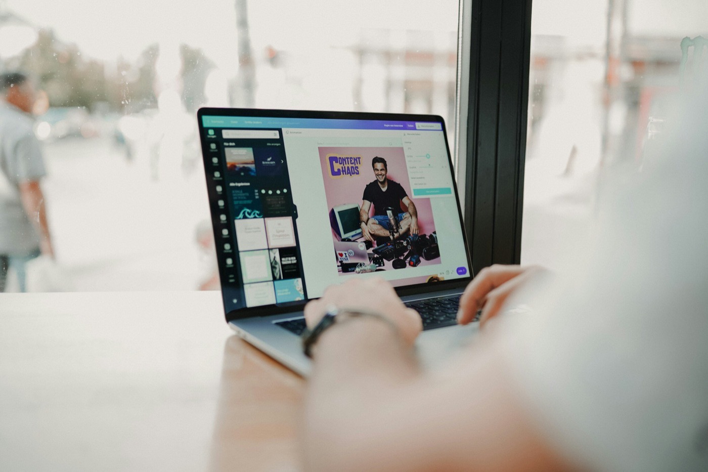 Person designing a 'Content Chaos' graphic on a laptop by a bright window